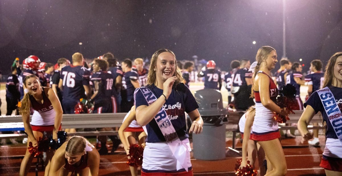 On the first football game of the season, Jayden Bresnan (12) laughs after performing a cheer in the rain. This was also Bresnan's senior night for cheer.