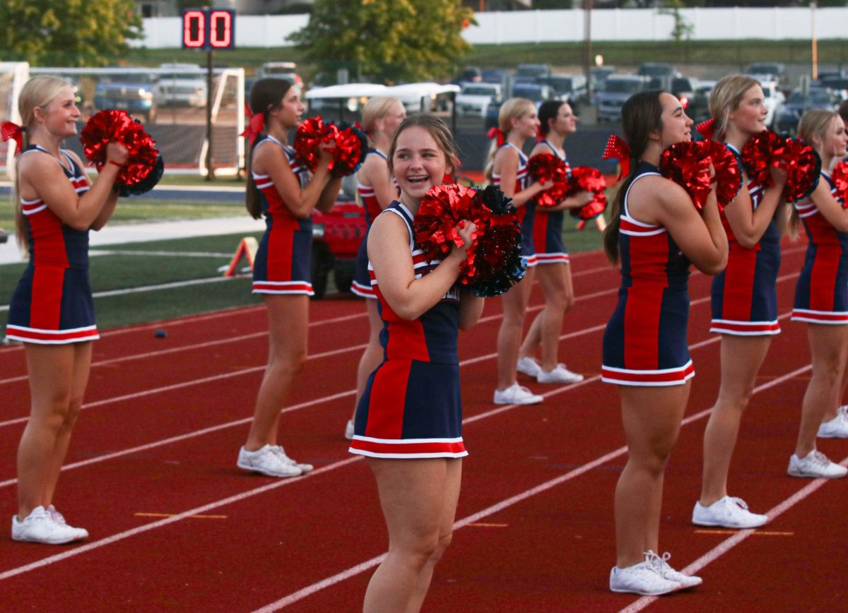 Kara Brockmann (10) looks over smiling while cheering at JV football game.