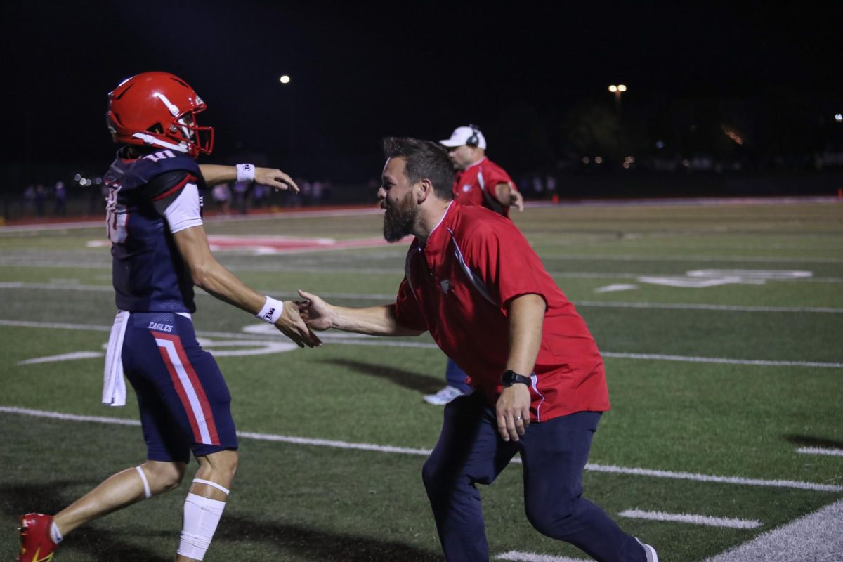 Assistant football coach Jeremy Tutterrow celebrates with quarterback Cody McMullen from a game last season. 