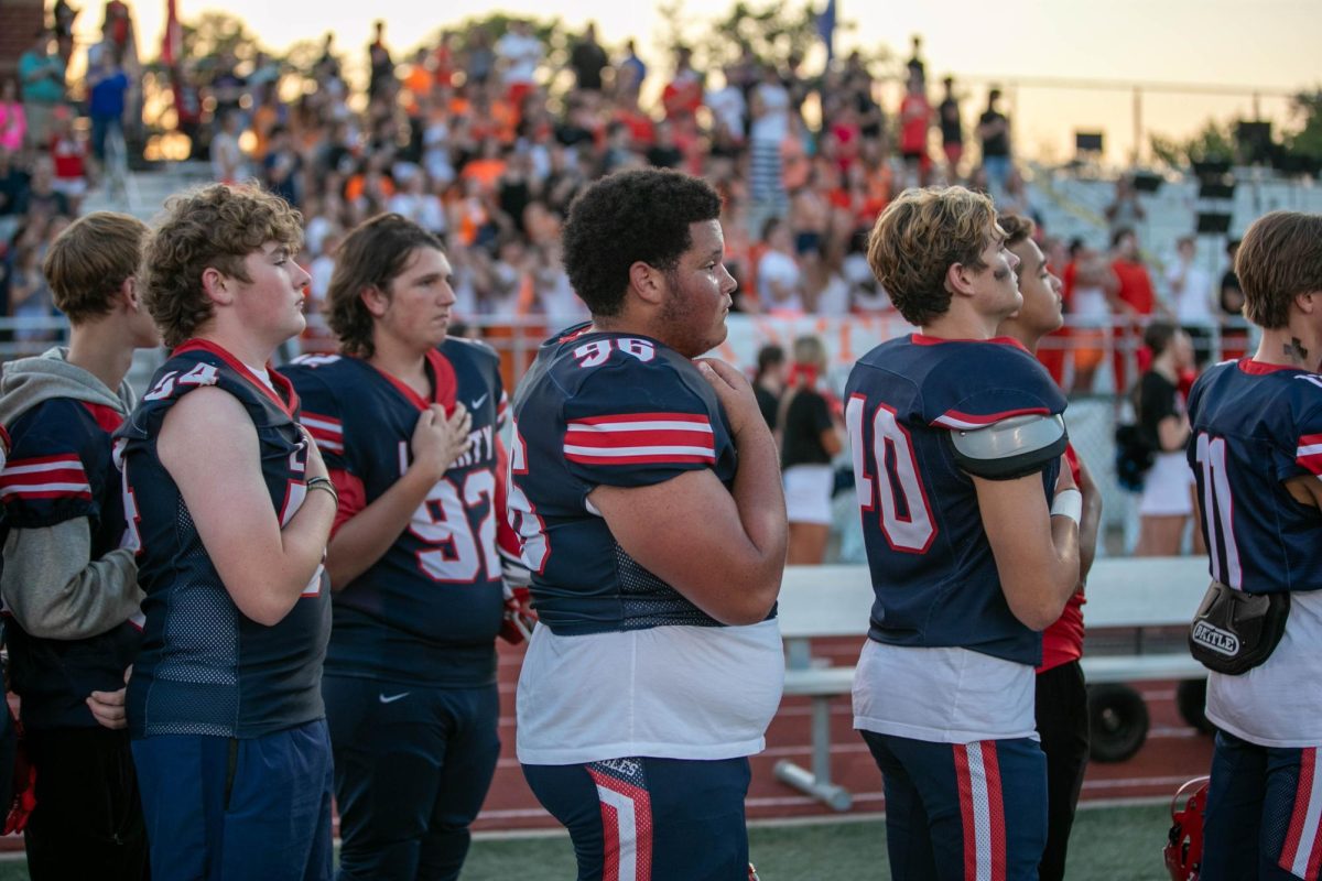 Quentin Luss (12) watches the flag, hand over heart, during the national anthem.