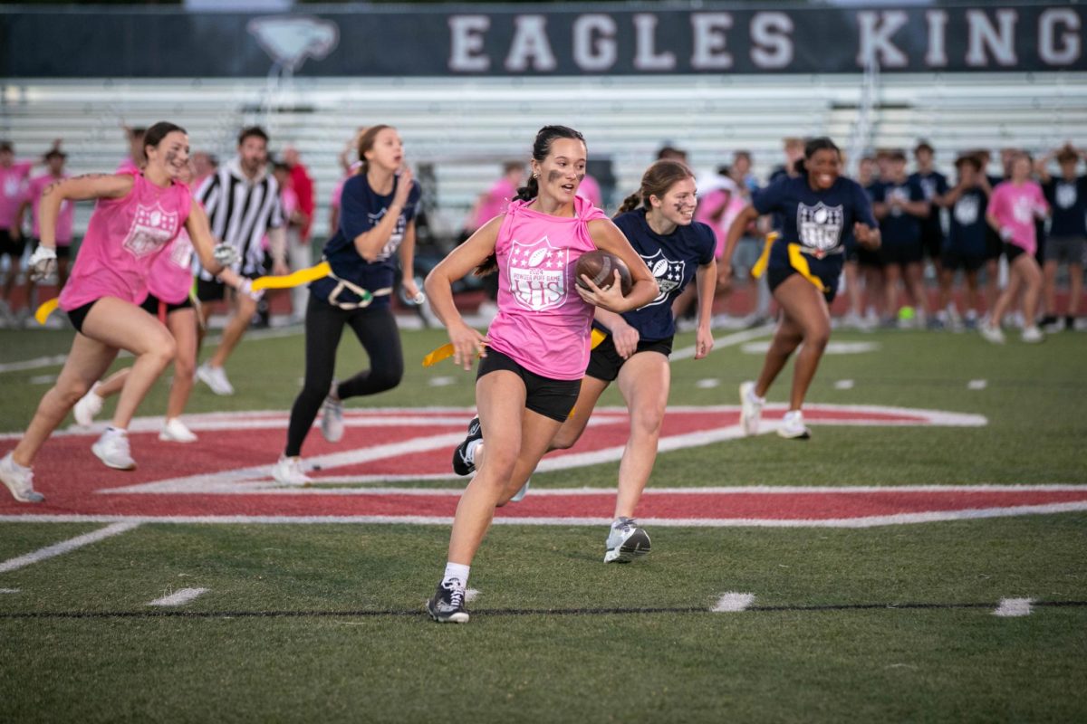 Payton Hemmer (12) runs past the 50-yard mark with the ball during annual powder puff game.