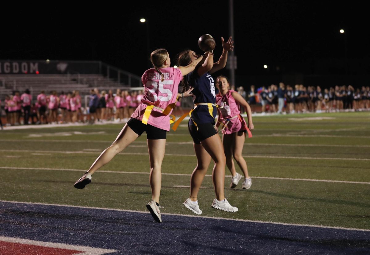 Sophia Gamm (11) (right) jumps up to intercept the ball from Lucy Lant (12) (left) during the annual powderpuff game on Oct. 2.