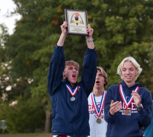 Landon Jones (12) holds up the varsity boys GAC Conference Champions plaque while celebrating at McNair Park.