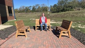 Patrick Nolan sits on one of the benches he built for the new Garden of Hope seating area.