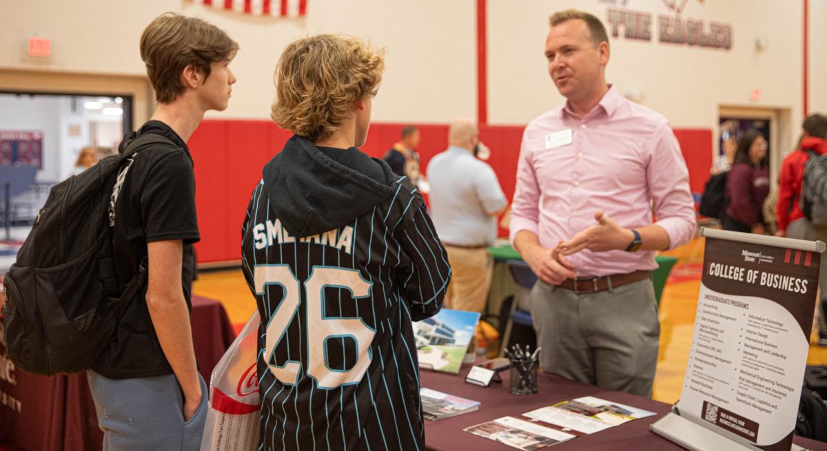 Two students chat with a representative from Missouri State's College of Business.