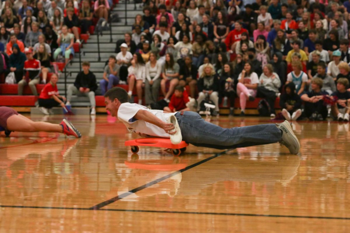 Teacher Mr. Hall rides on a scooter during the teacher race.