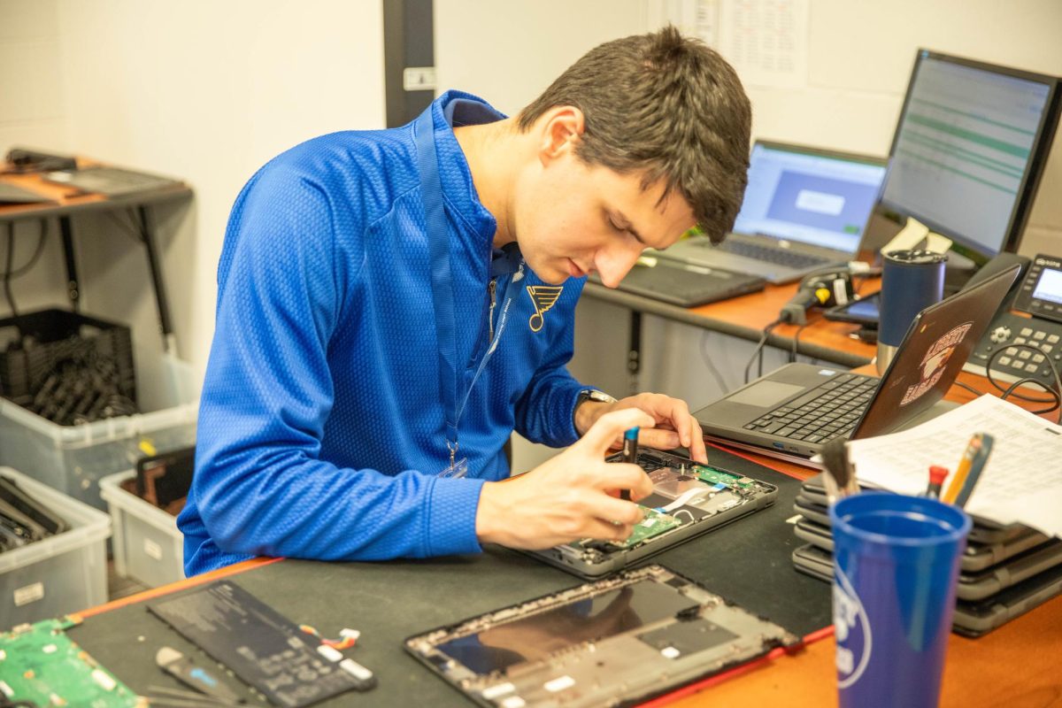 Grant Descher opens up and using tools to fixing a student Chromebook.