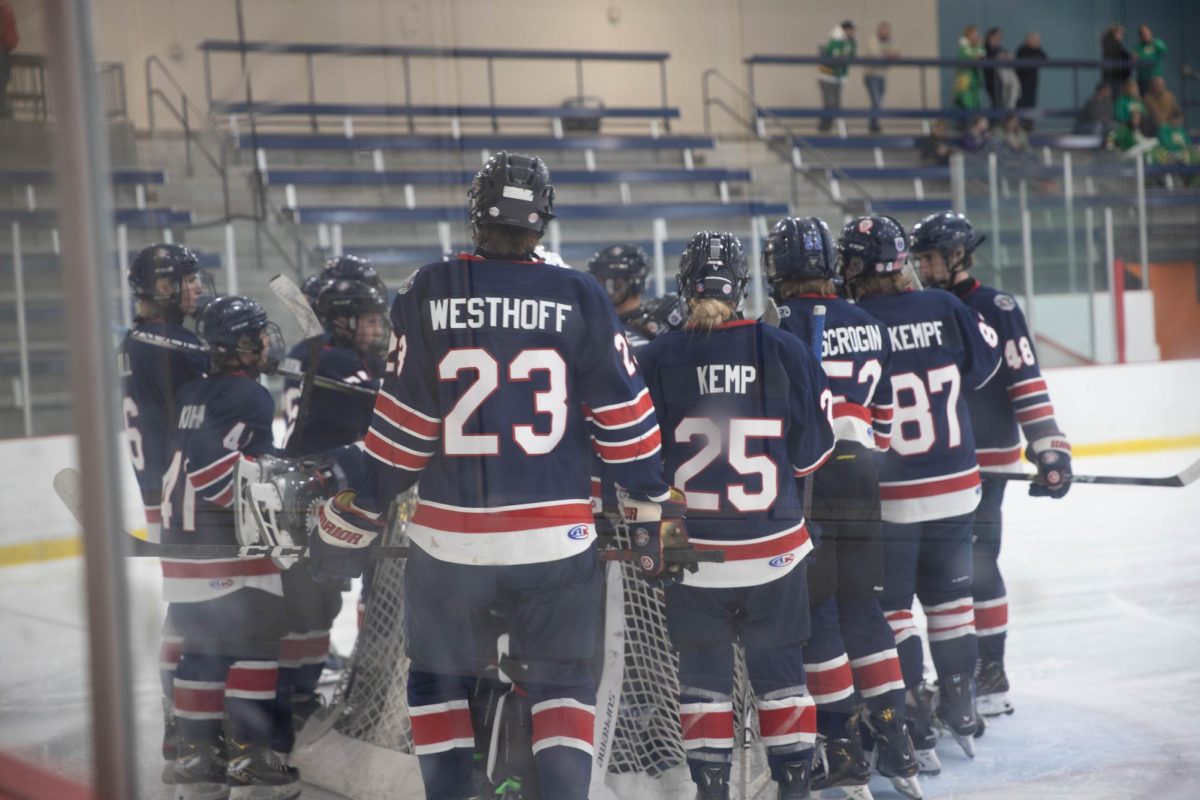 The varsity hockey team gathers around their goal at the end of warm-ups.