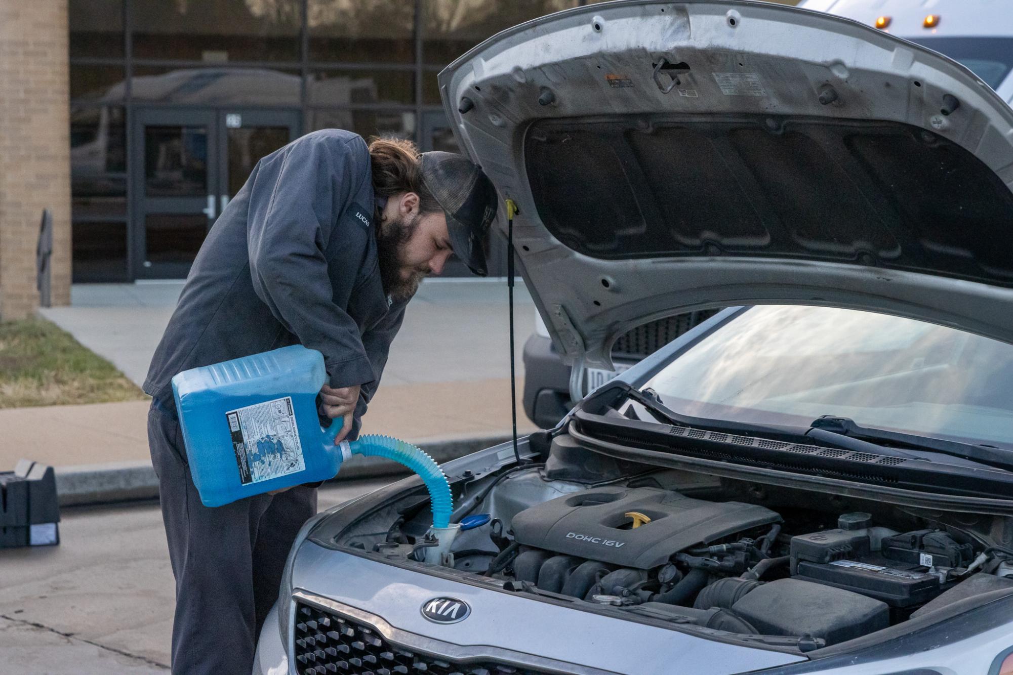 Lou Fusz employee adds coolant to Wheelers car while also preparing it for an oil change.