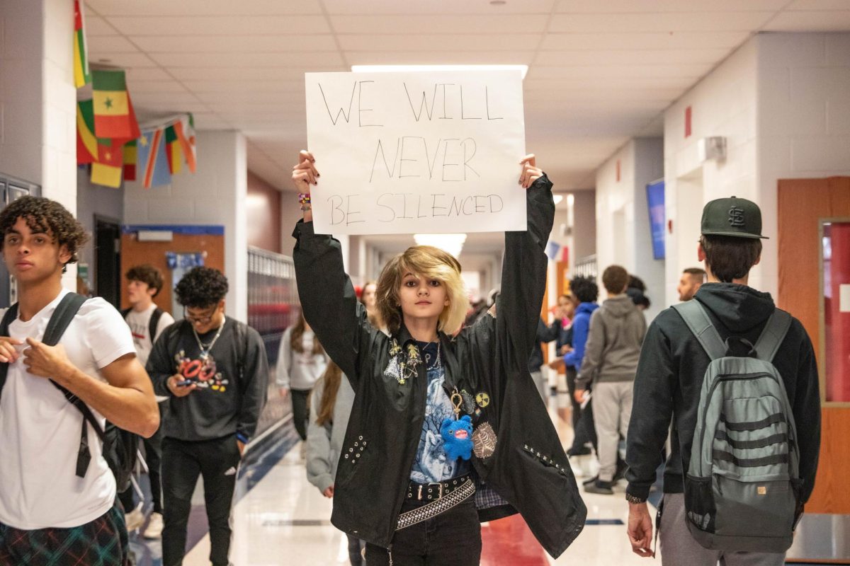 Kay Cooper (9) holds sign in the hallway while students walk past him while he protests the ignorance of trans voices.