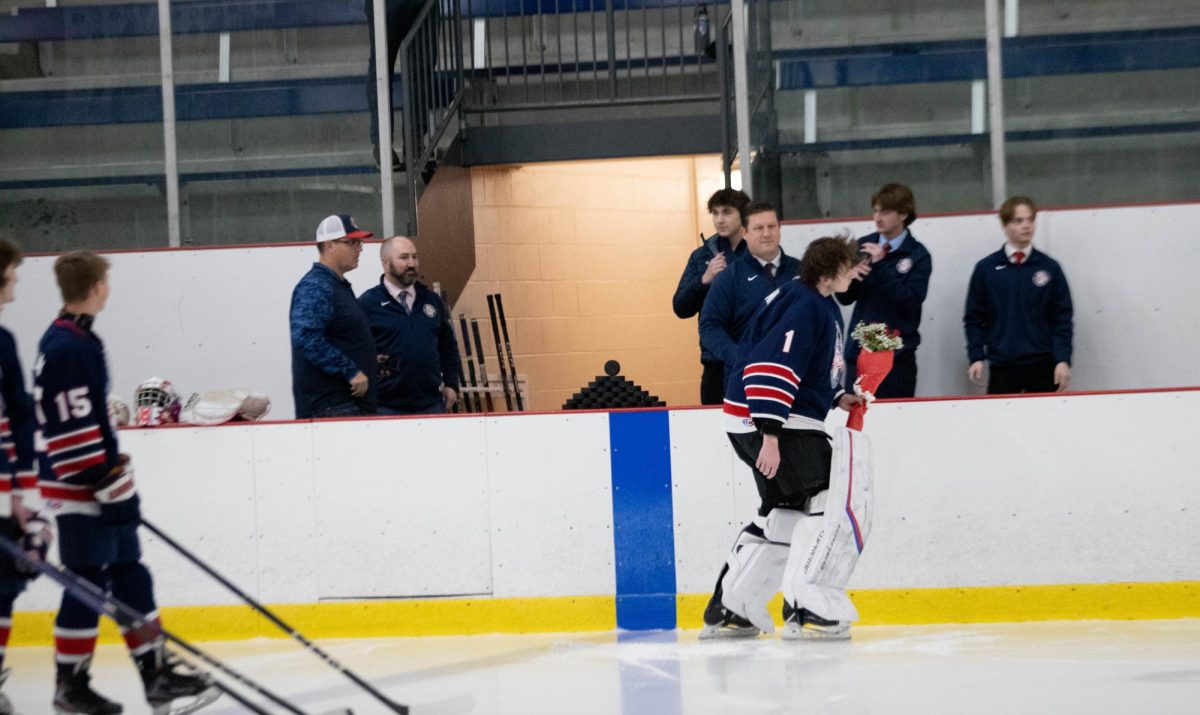 Ben Teismann skates over to parents after receiving flowers from head coach.