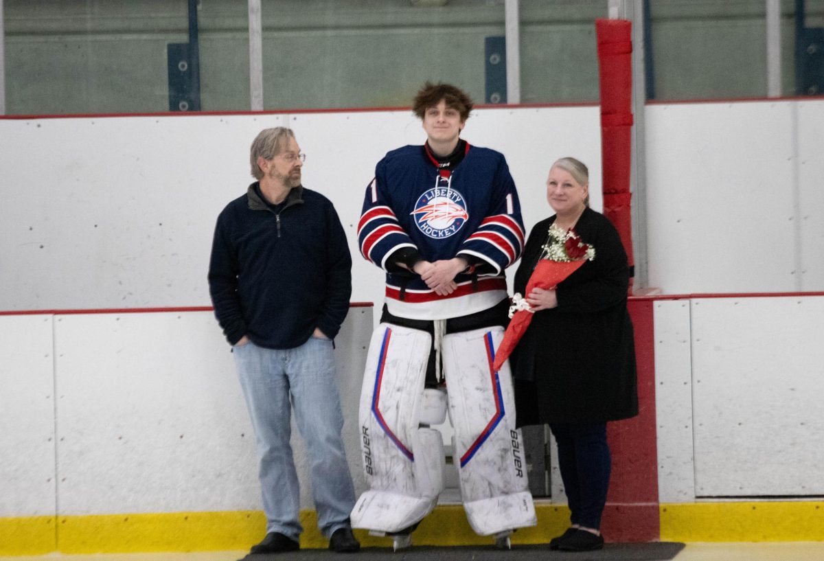 Ben Teismann poses for pictures with parents during senior night ceremony. 