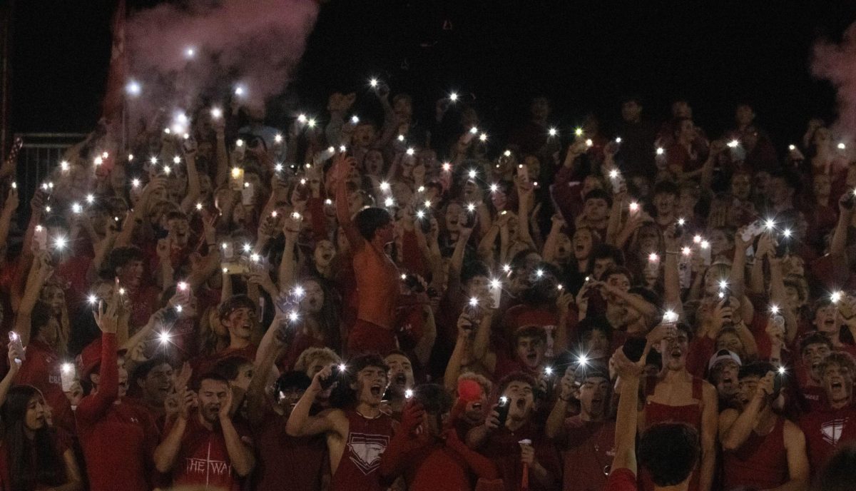 The student section gets excited and loud as they turn on their phone flashlights at the annual Red Out game. 