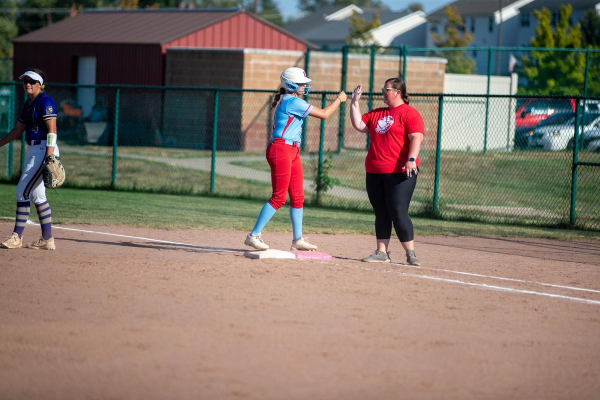 Charlotte Thornton (12) high fives her first base coach after hitting a single. 