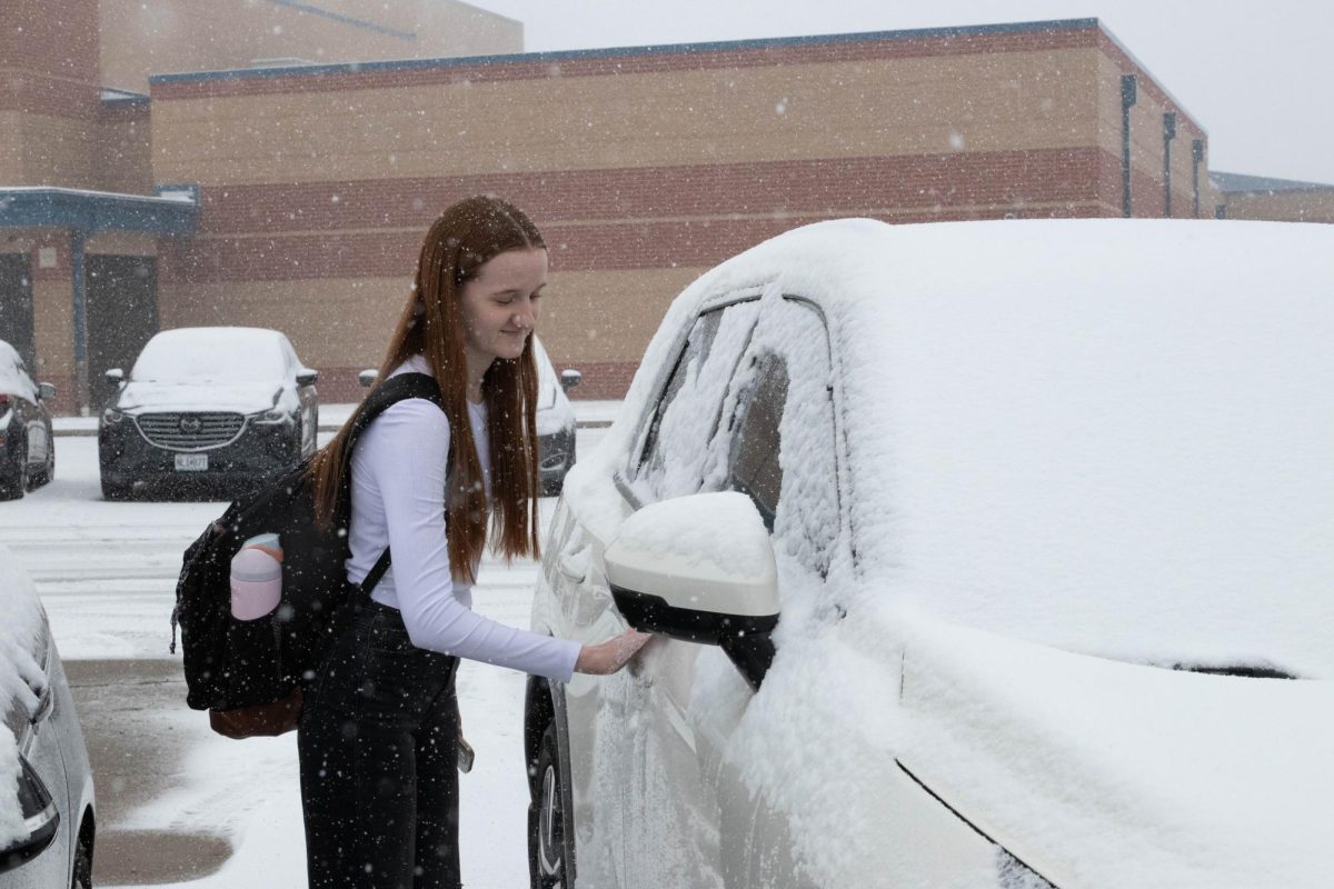 Brynn Galliher (11) wipes the snow off of her car. 