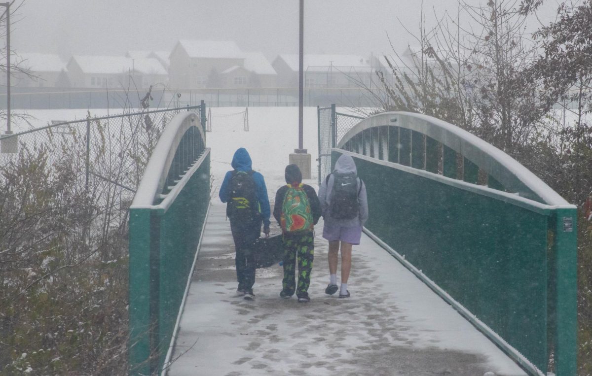 Three students walk across the snowy bridge.