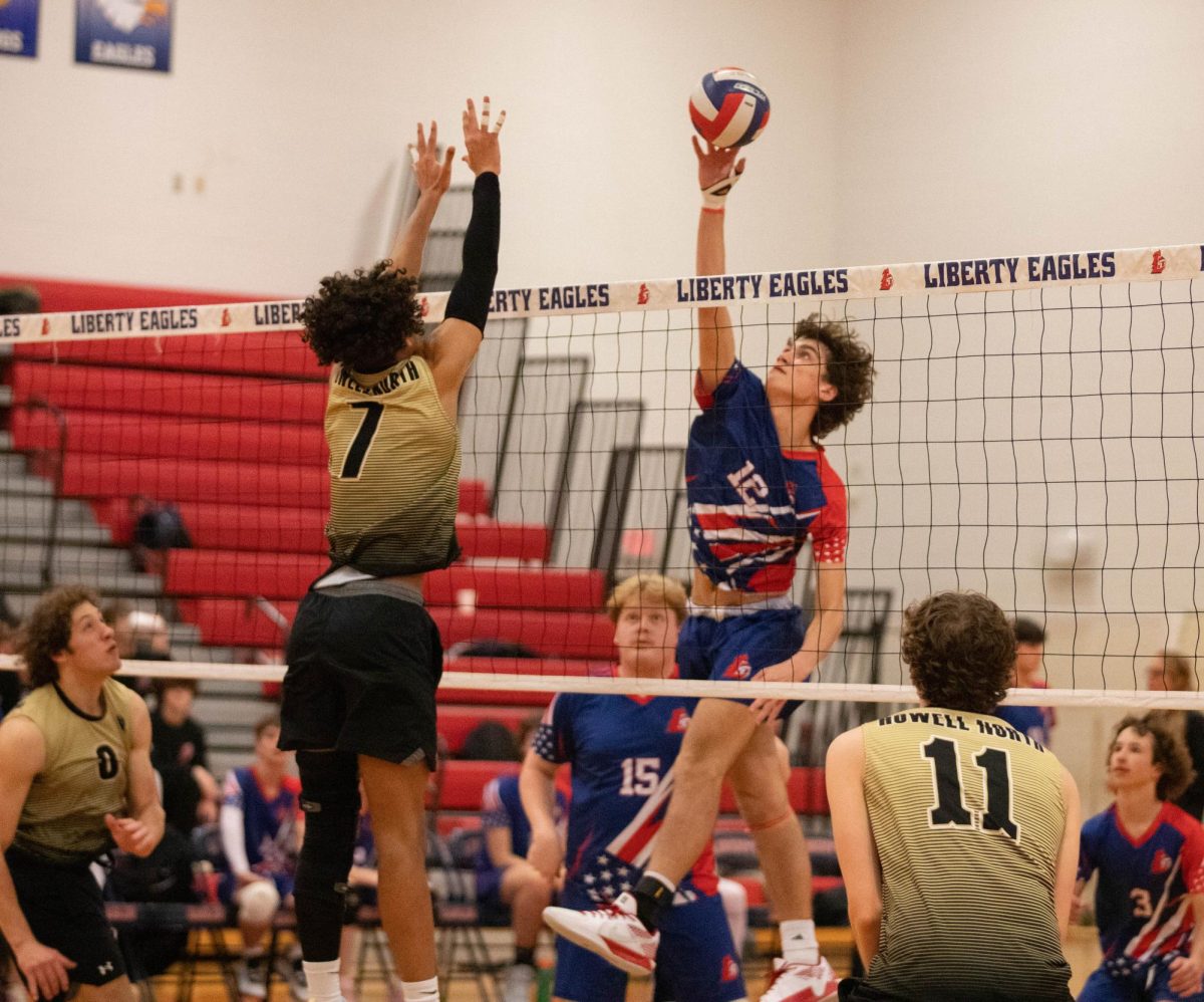 Caiden Stumbaugh (12) jumps to spike the ball against Holt High School.
