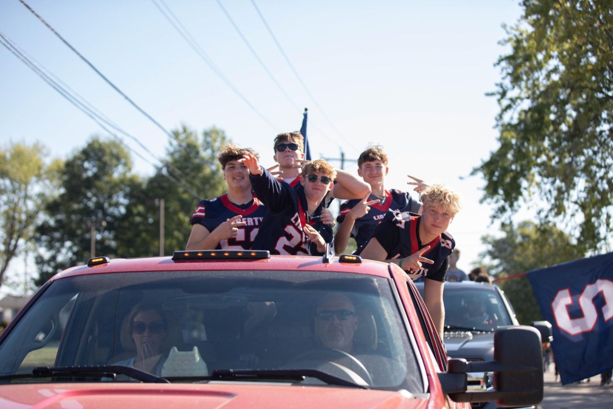 Collin Scism (11) and other football players stand in the back of their football float during the homecoming parade.