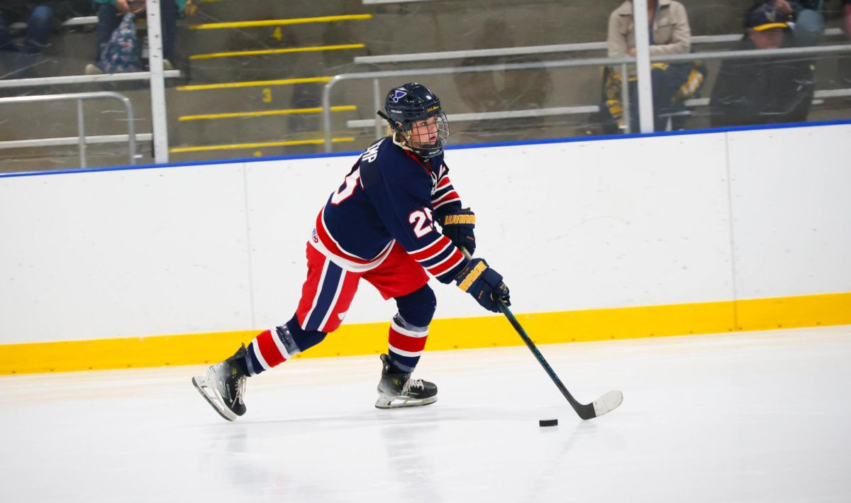 Diana Kemp (12) looks towards the goal while skating with the puck.