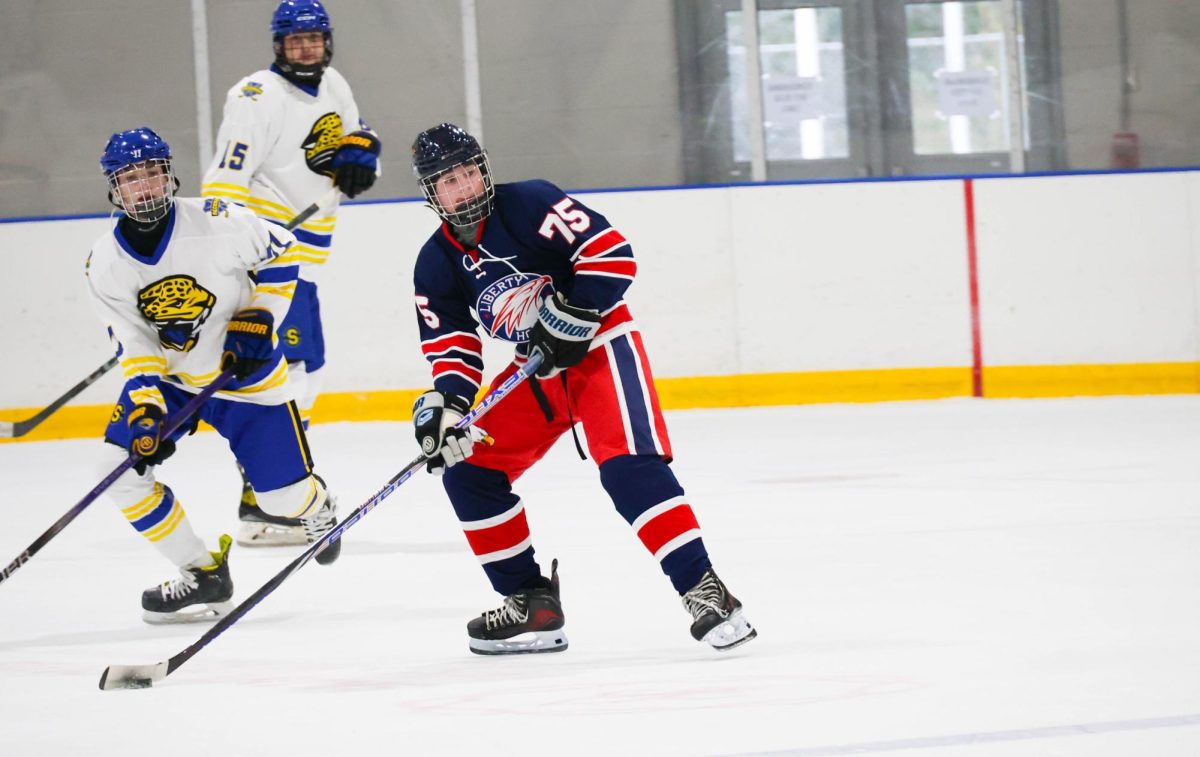 Blaine Schroeder (9) looks across the ice towards his teammate before passing the puck.