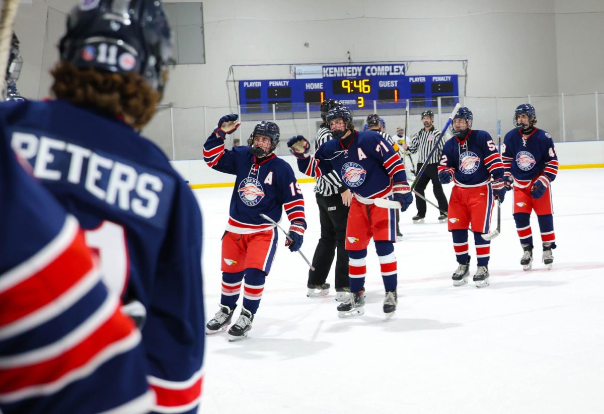 Greyson Howarth (12) skates towards the bench for fist bumps with his teammates behind him after scoring a goal.