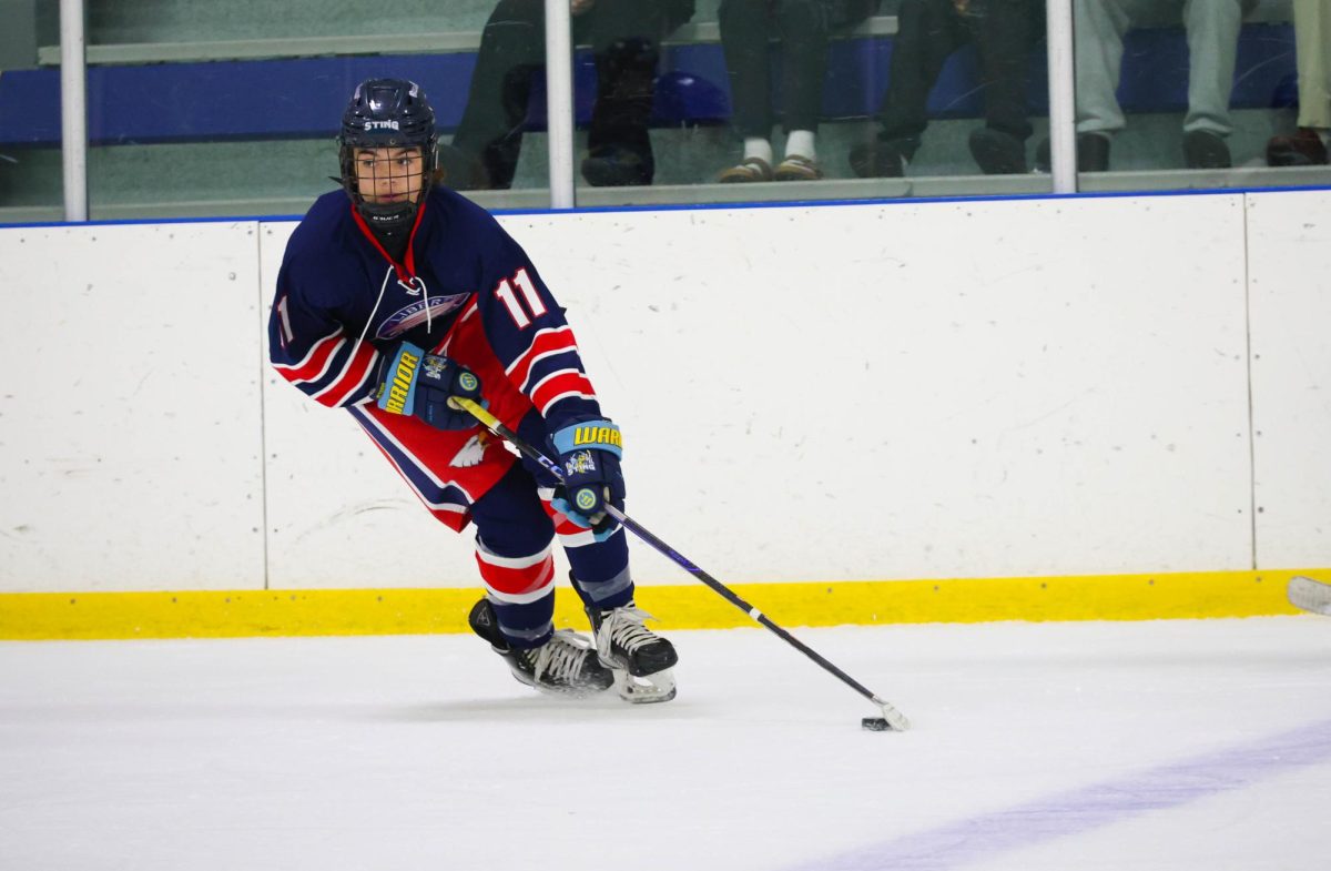 Ethan Peters (9) looks across the ice while handling the puck.