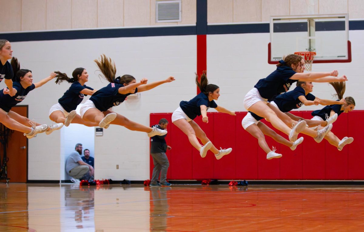The freshman cheer team all does a toe-touch during a halftime. 