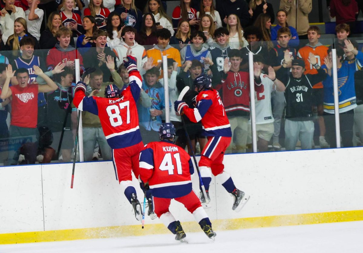 Lucas Kempf (12), Nicholas Kuhn (11), and Connor Casella (11) jump against the glass in front of the student section after scoring a goal. The team tied this game 2-2 against Timberland on Nov. 25.