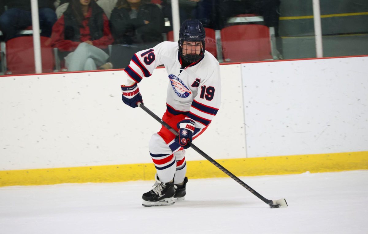 Greyson Howarth (12) looks across the ice to his teammate while handling the puck.
