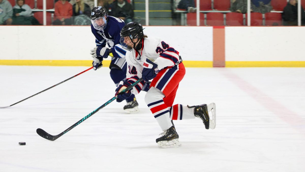 Chase Dickerson (9) skates down the ice with the puck while a Francis Howell Central player skates towards him. 