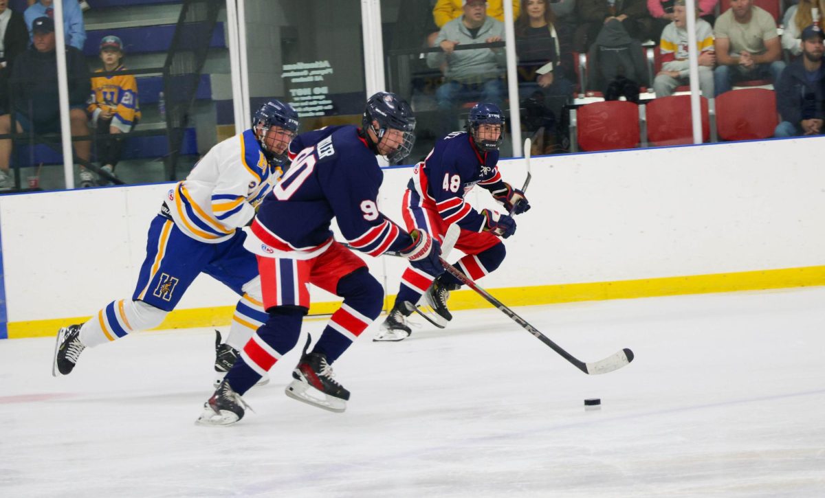 Mason Nickler (10) skates down the ice with the puck while Garrett Katz (11) looks over at him.