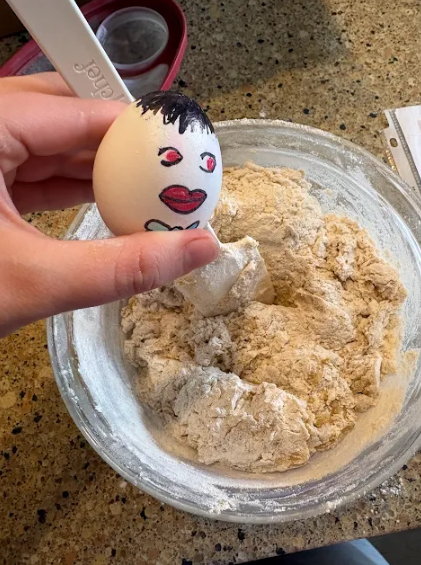 Hugo the egg helps to mix a bowl of cookie batter.