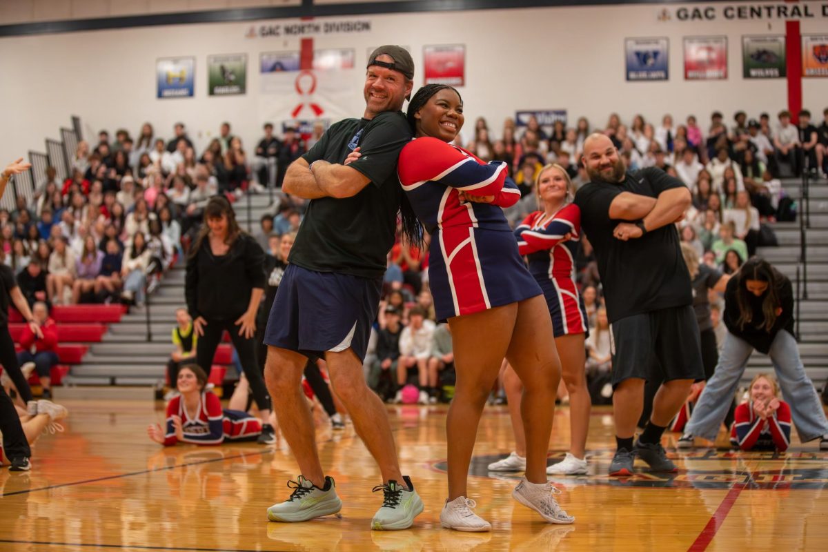 Coach Gregory Franklin and Aniyah Wooten (12) face back-to-back during the cheer/teacher dance at the coaches vs. cancer assembly.
