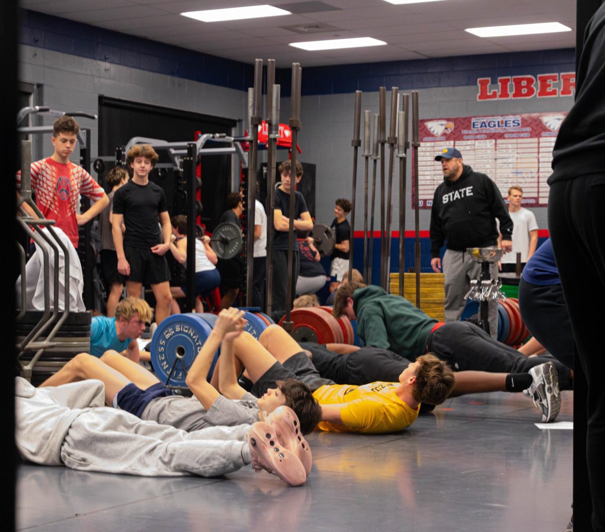 Returning freshman football players do crunches on the floor. 