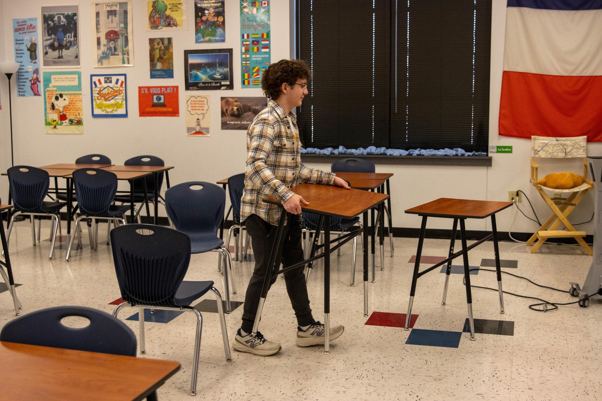 James Skibinski (10) helps to move desks to set up for the Scholar Bowl competition.