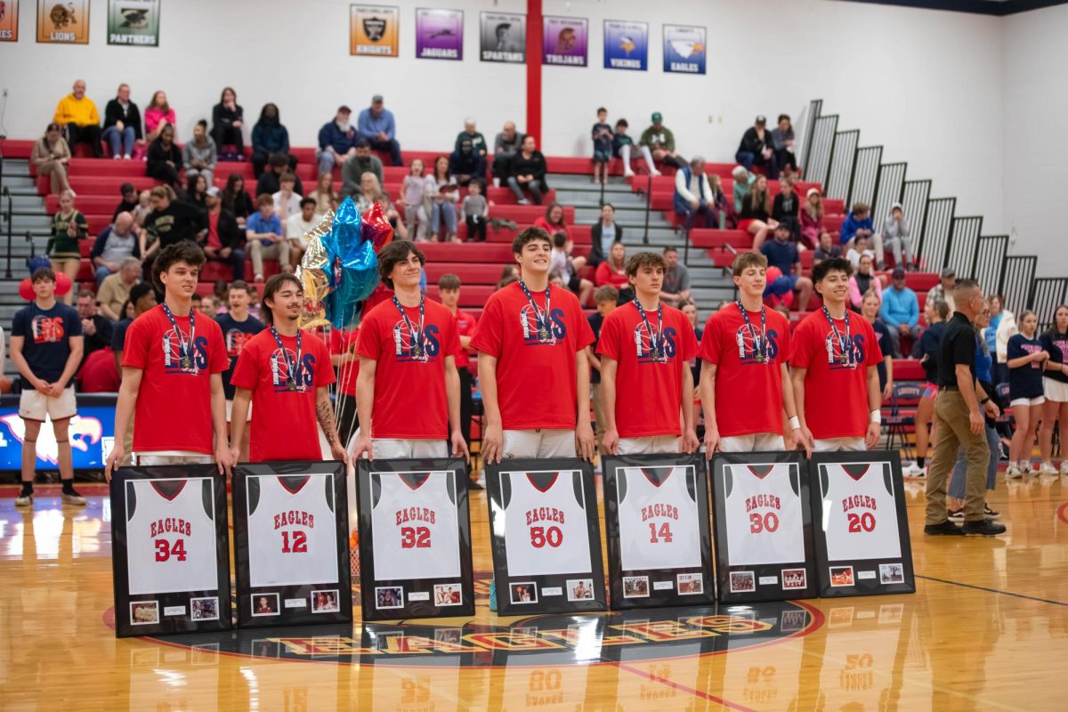 Boys basketball seniors pose with their framed jerseys on senior night