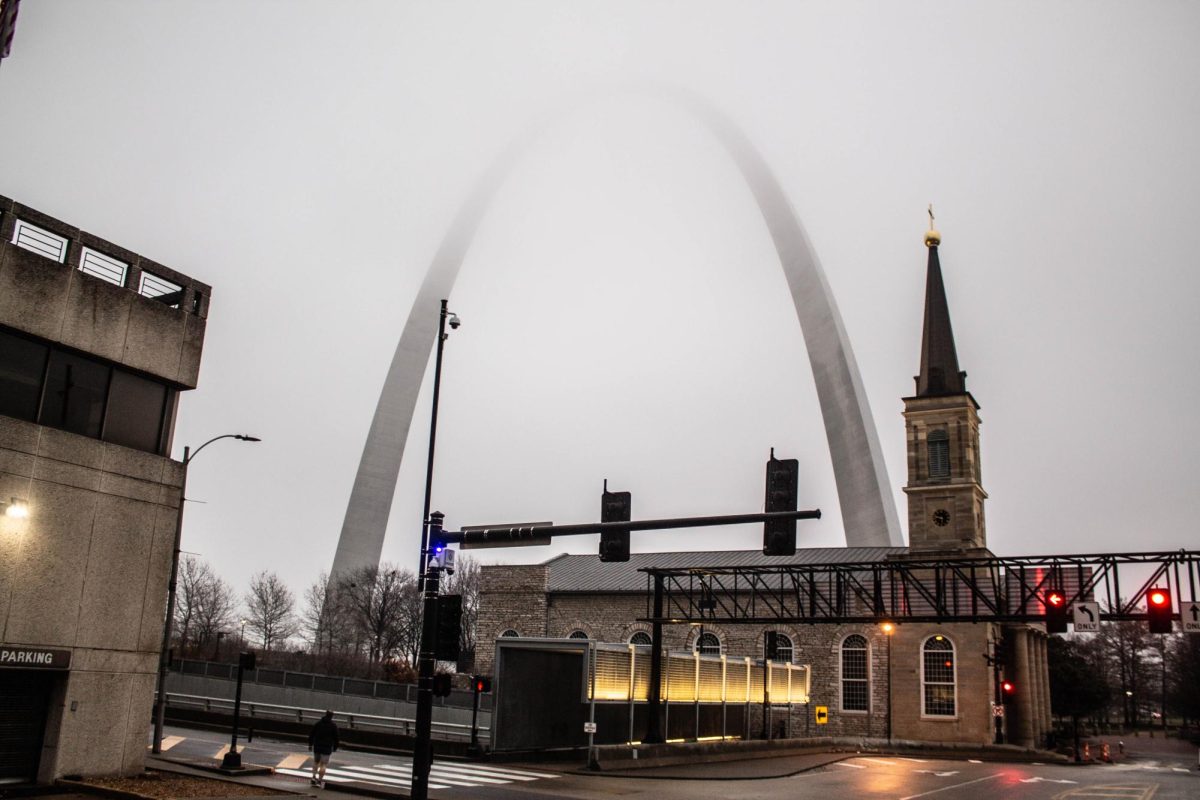 The Arch of St. Louis stands tall on a foggy city day. 