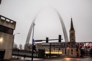 The Arch of St. Louis stands tall on a foggy city day. 