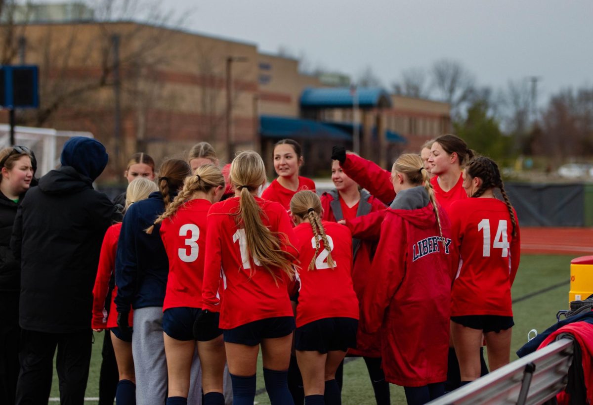 The varsity girls soccer team are in a huddle to get hype before the game starts.