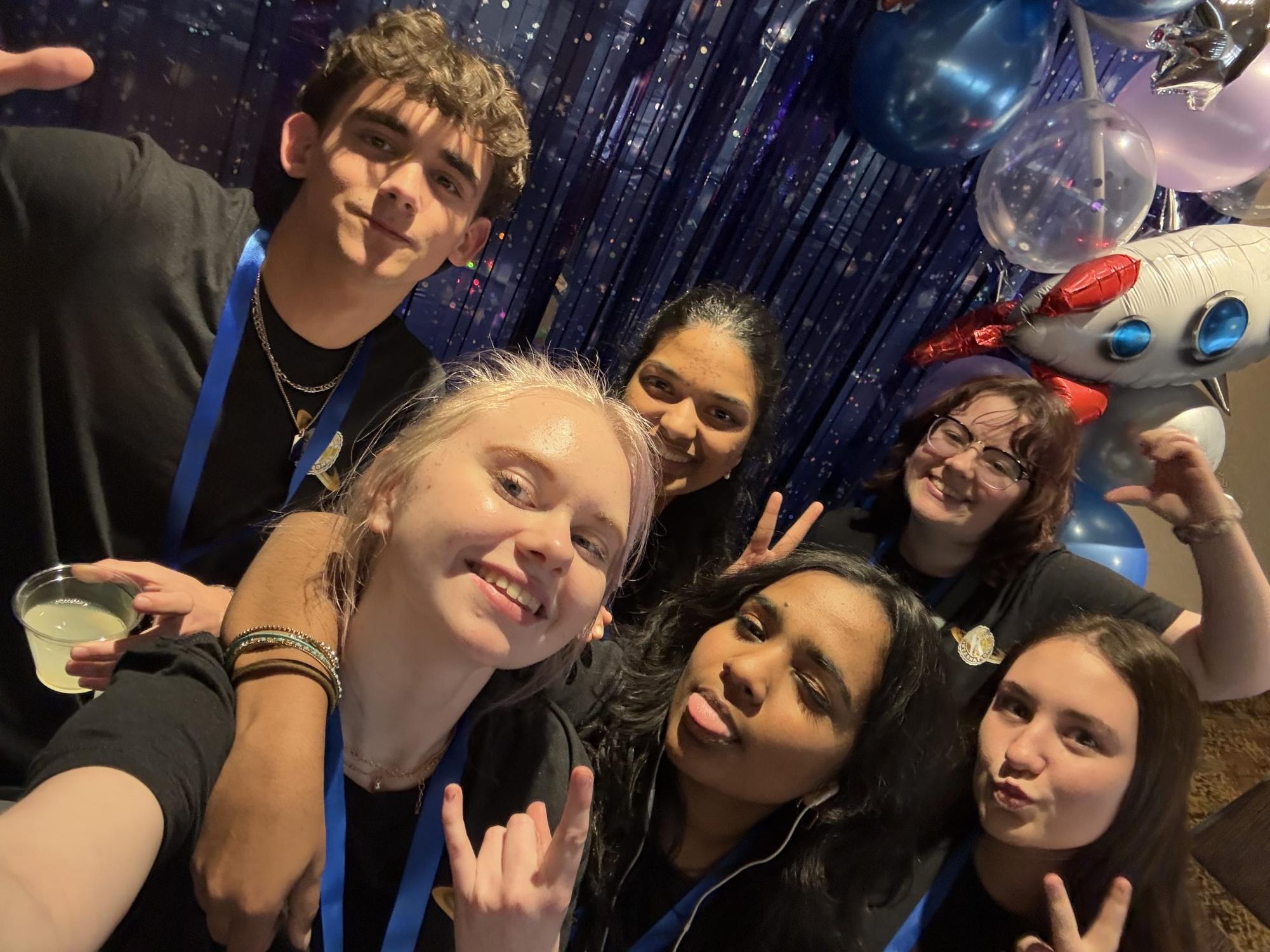 Key Club DLC attendees Yago Taraud, Lorelei Wise, Loukya Vaka, Ella Quinney, Navya Manchala, and Alexis Miller pose in front of photo booth that dons the space theme of the conference.