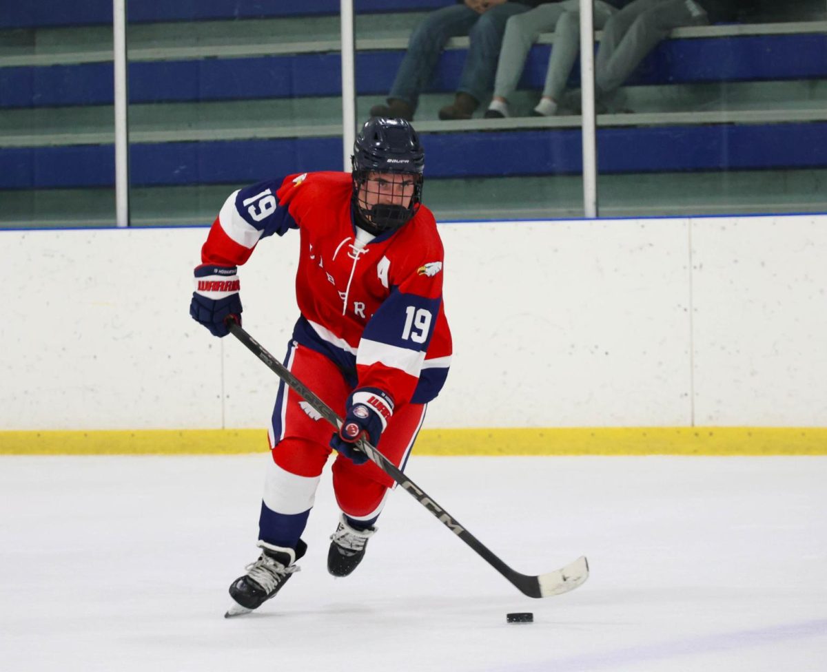 Greyson Howarth (12) stick handles the puck  while skating towards Liberty's offensive zone.