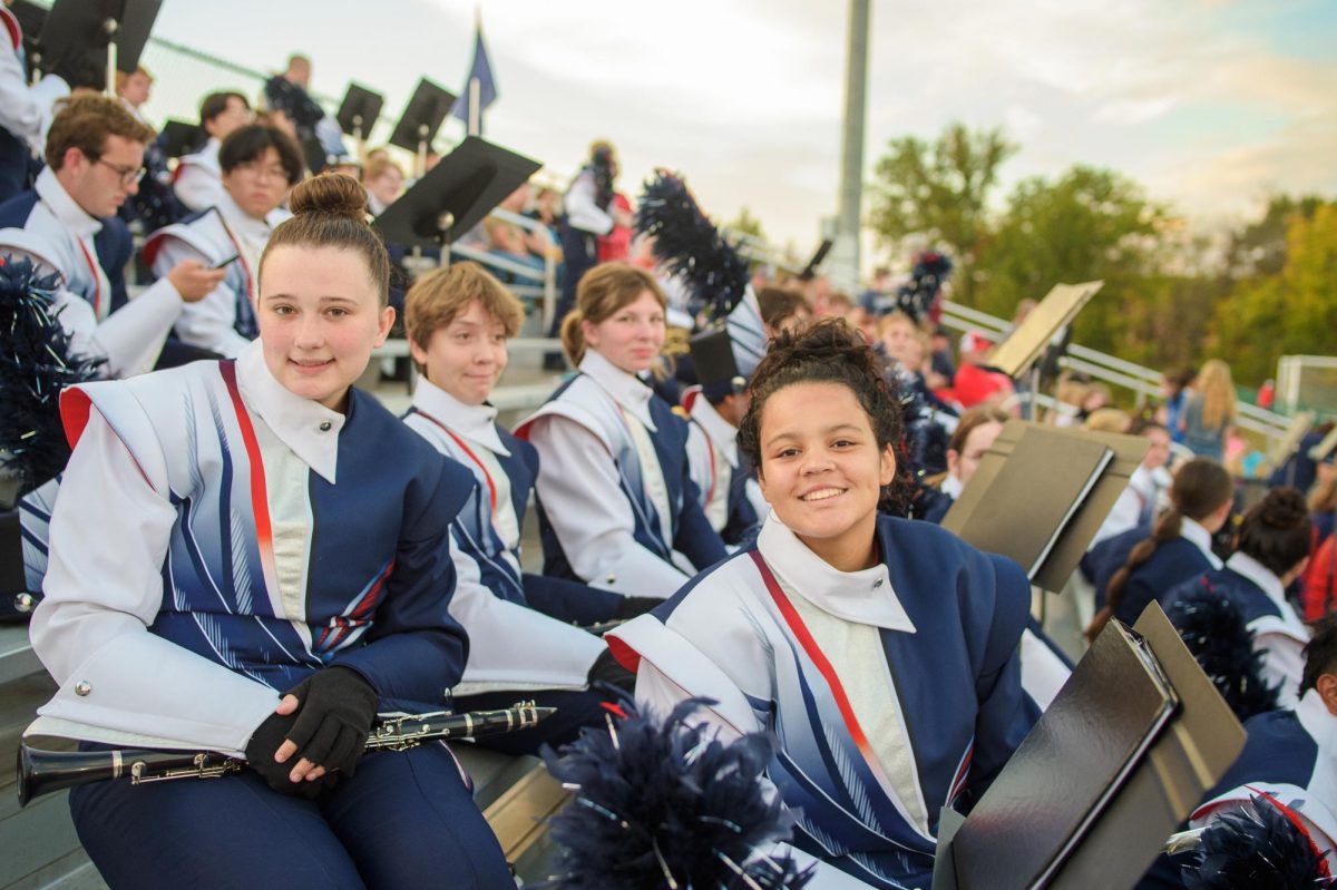 Madeline Mitchell and Keron Bowman pose for a picture in the stands while playing band tunes during a football game.