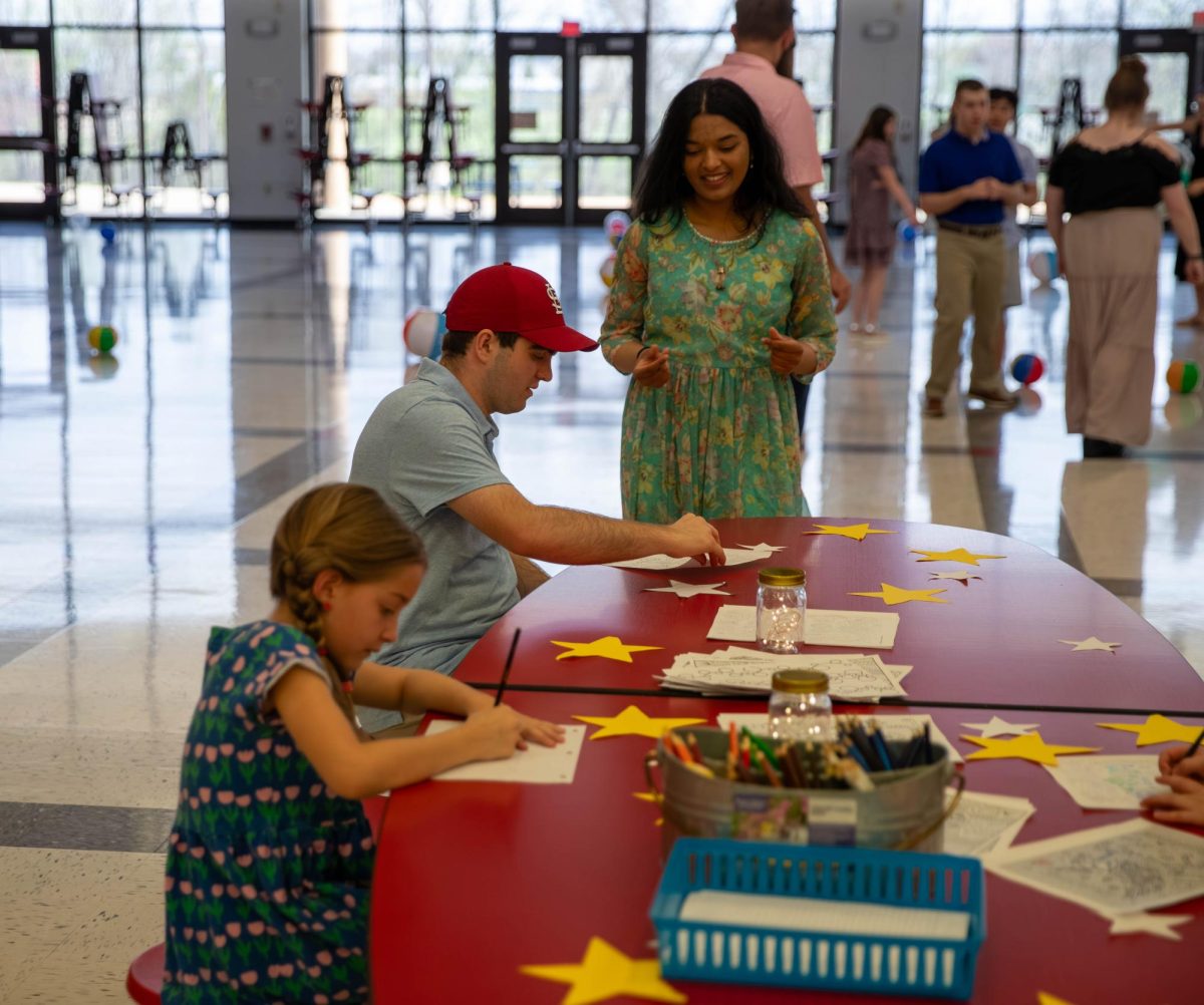 Loukya Vaka (12) helps Luke Medlar (12) work on a coloring page during the All of Us dance.
