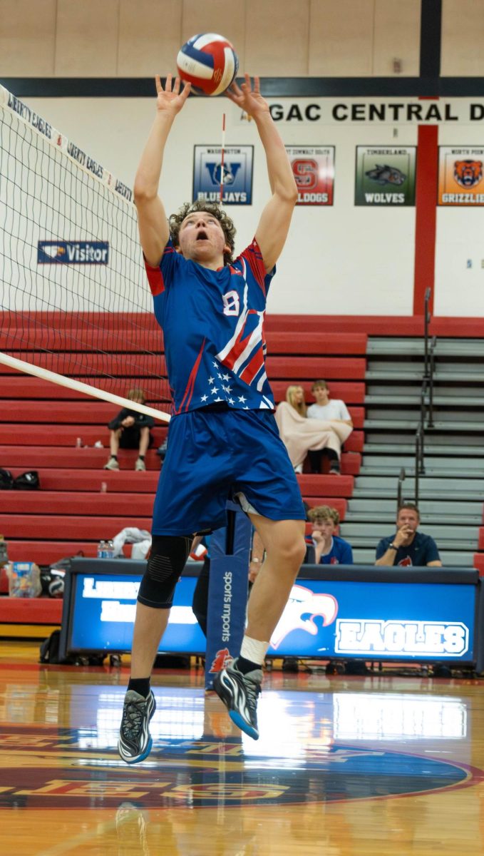 Nicholas Hostetter (11) sets the ball for his teammate to hit.
