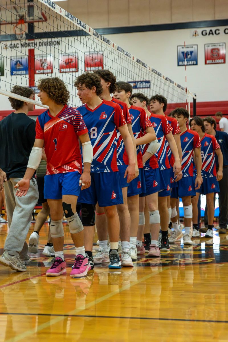 Varsity boys volleyball players high-five Howell North after a win.