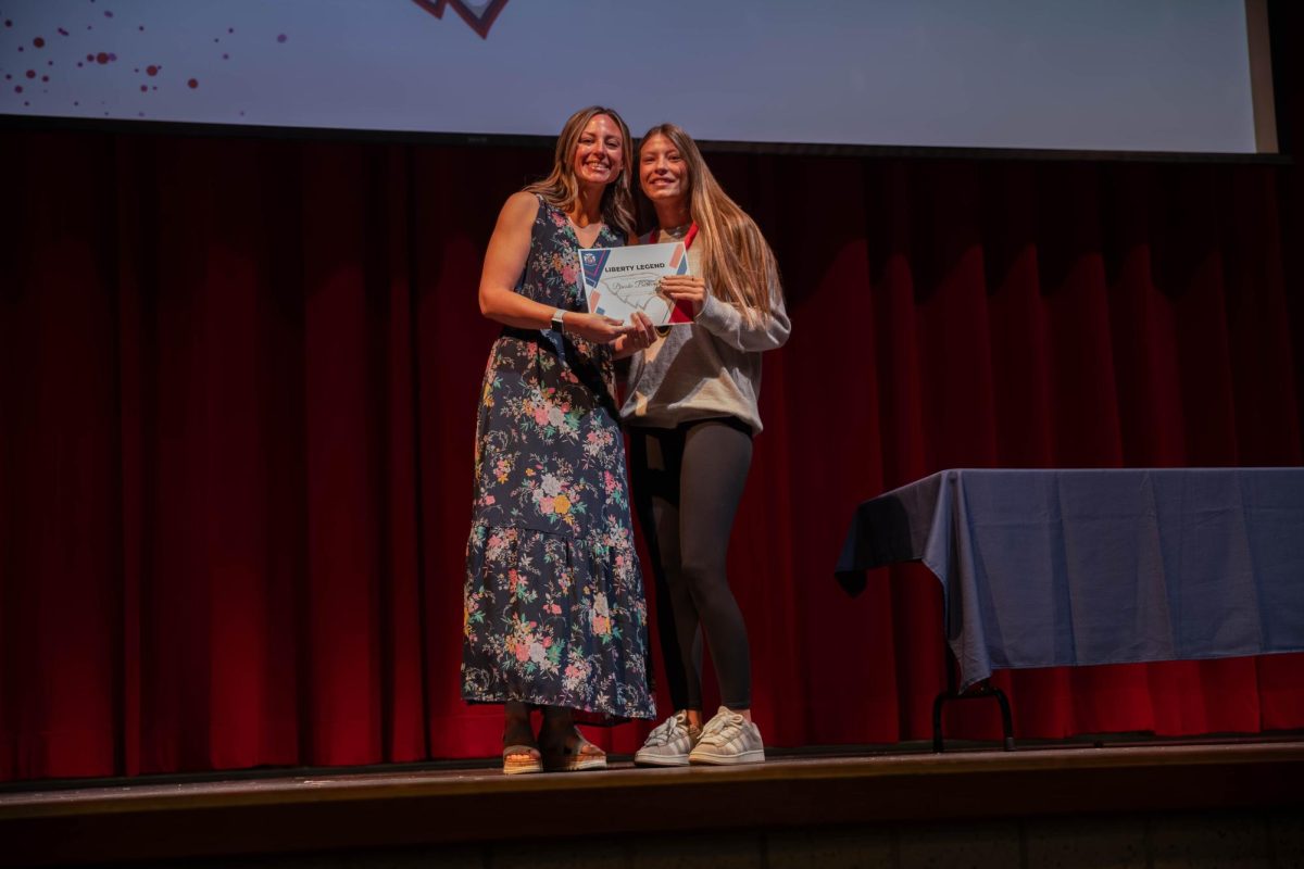 Nicole McFadden hands Brooke Burkemper (11) her Liberty Legend certificate showing all that she has done for her class and the school. 