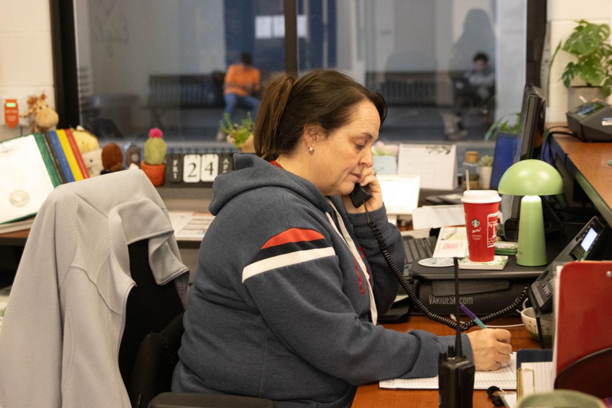 Secretary Colleen Grams takes a phone call from a parent calling their child out of school early due to the storms.