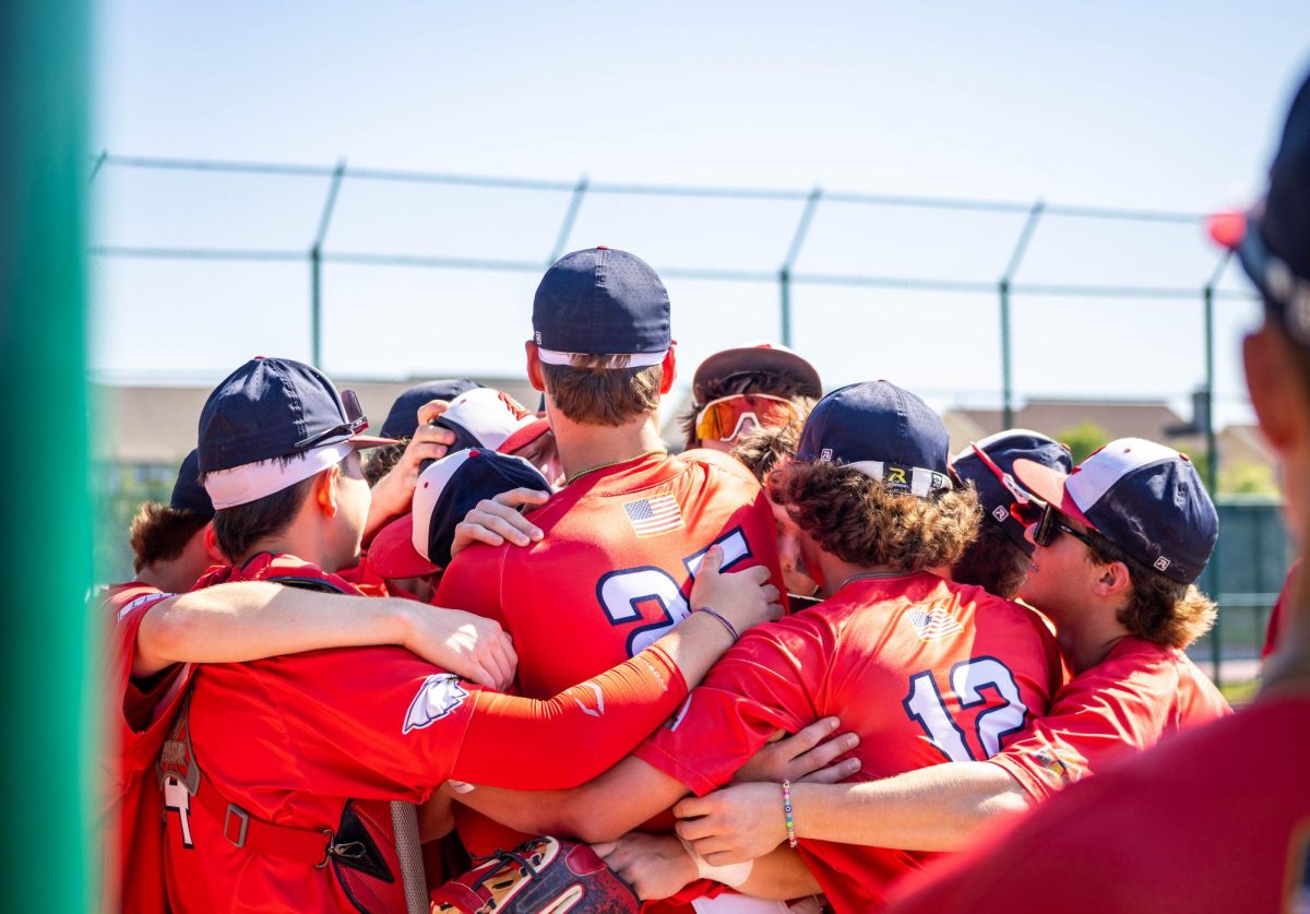 The varsity baseball team hugs each other before the game starts.