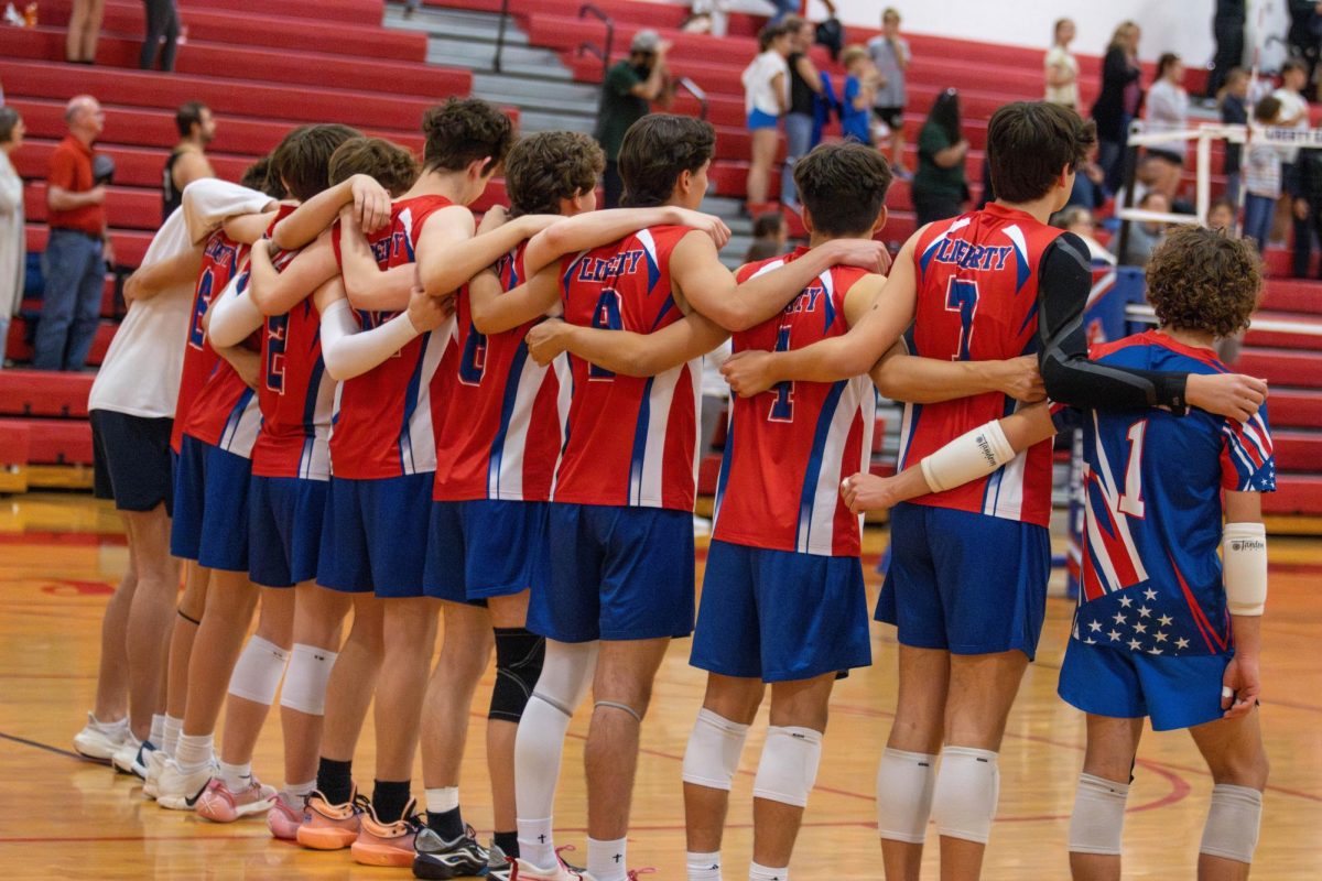 The volleyball team is lined up listening to the National Anthem.