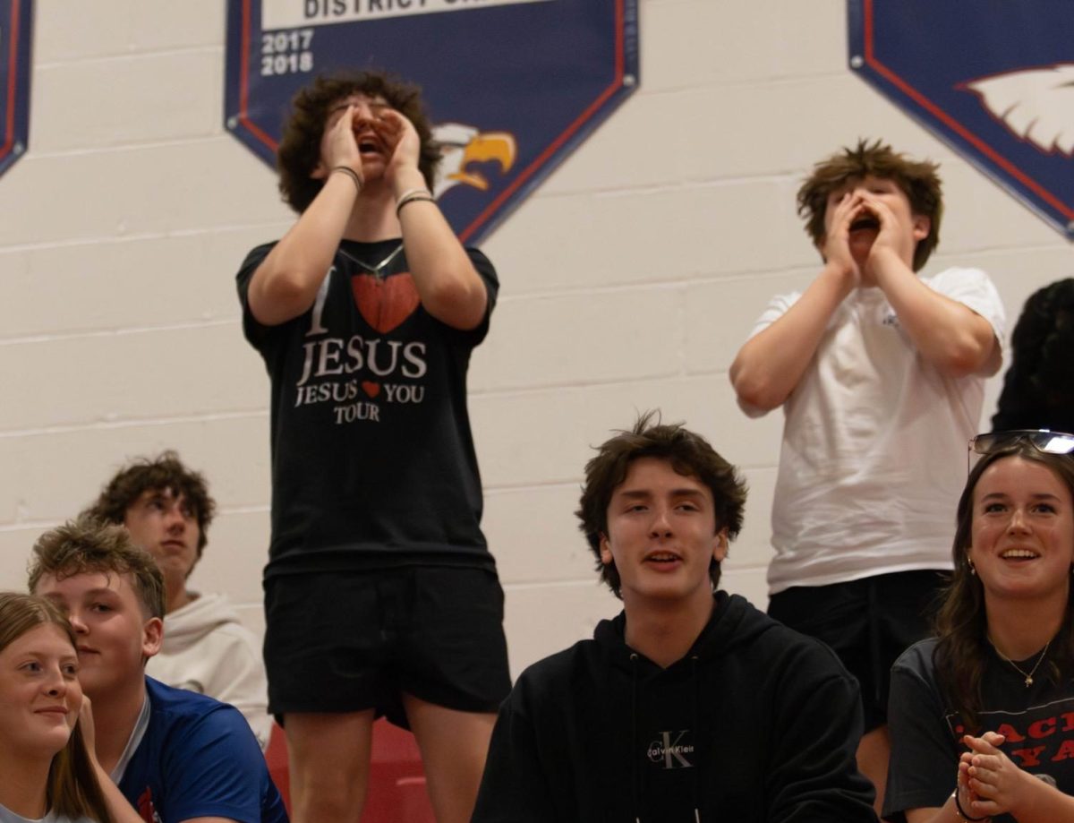 Liam Grams (left) leads student's in a chant to encourage the team.